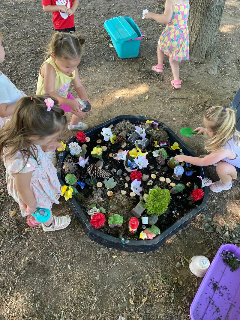 Children planting flowers in a tub of soil