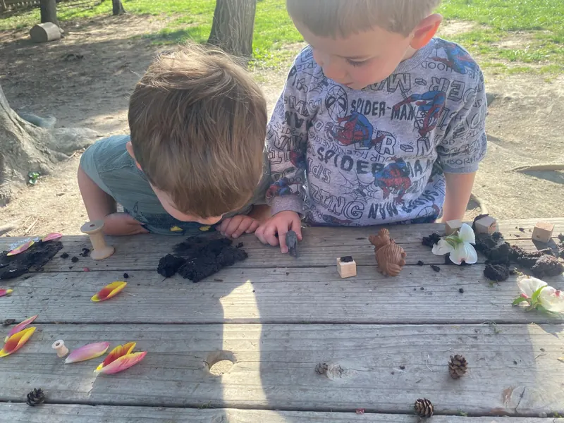 Two boys exploring soil and seeds on an outdoor table